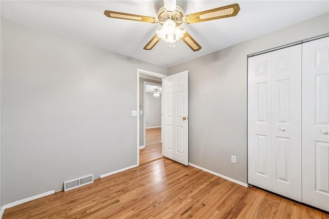 unfurnished bedroom featuring baseboards, visible vents, a ceiling fan, light wood-style floors, and a closet