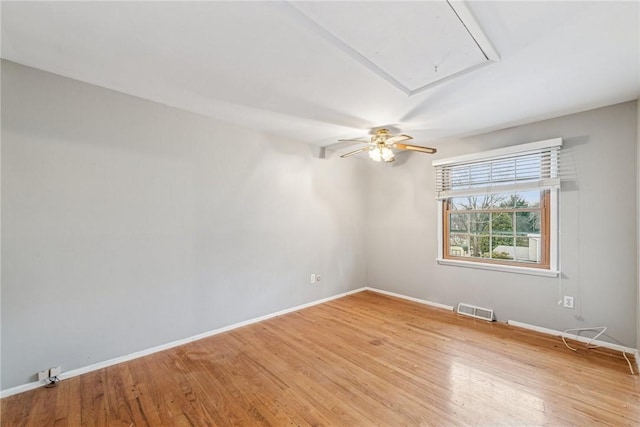 spare room with baseboards, light wood-style flooring, visible vents, and attic access