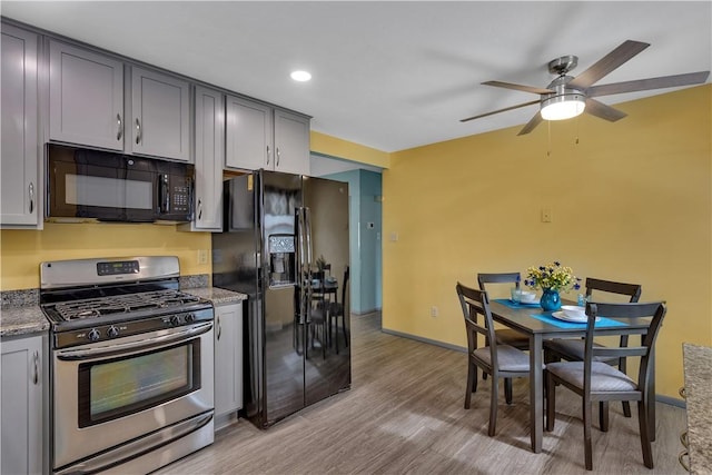 kitchen featuring gray cabinets, black appliances, light stone countertops, light wood-type flooring, and baseboards