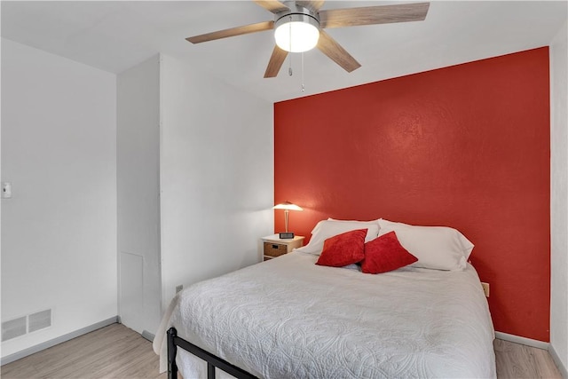 bedroom with light wood-style floors, baseboards, visible vents, and ceiling fan