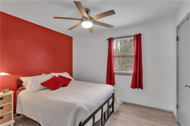 bedroom with ceiling fan, light wood-type flooring, and baseboards