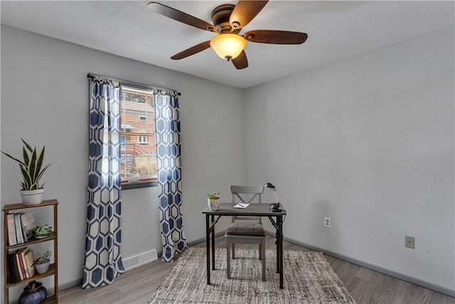 office space featuring light wood-style flooring, visible vents, ceiling fan, and baseboards