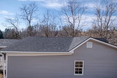 view of property exterior featuring a garage and roof with shingles