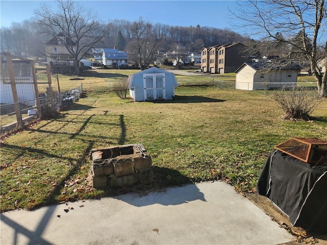 view of yard featuring a storage shed, fence, and an outbuilding