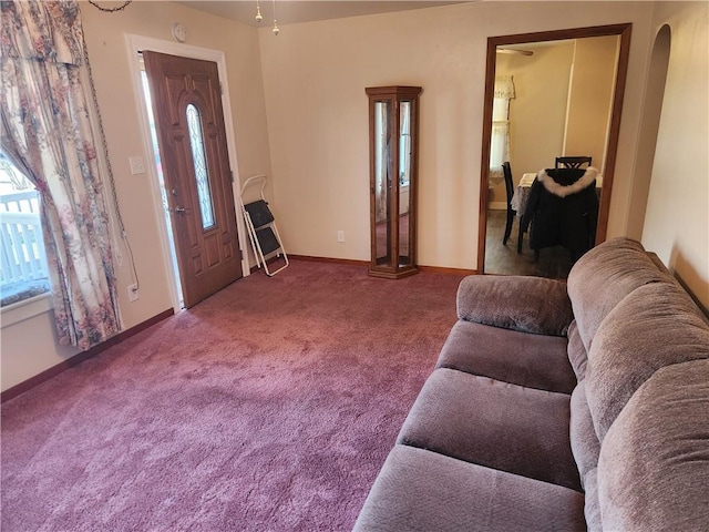 carpeted living room featuring arched walkways and baseboards