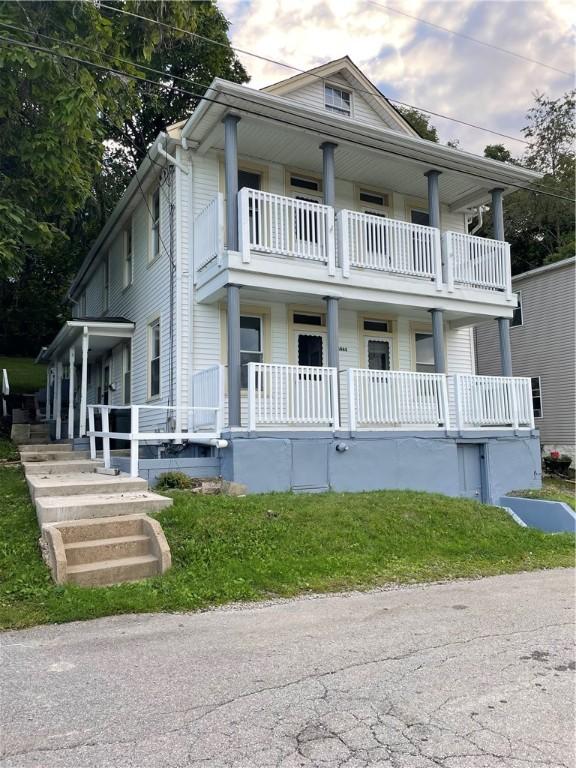 view of front of property with a porch, a front yard, and a balcony