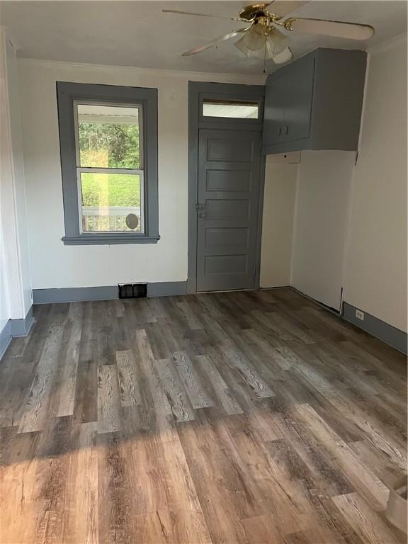 spare room with baseboards, visible vents, crown molding, and wood finished floors