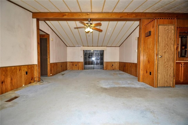 unfurnished living room featuring carpet floors, wood walls, lofted ceiling with beams, and a wainscoted wall