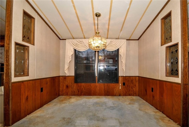 unfurnished room with a wainscoted wall, carpet, a chandelier, and wood walls