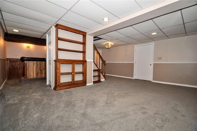 finished basement with carpet floors, stairs, and a paneled ceiling