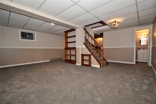 finished below grade area with a paneled ceiling, carpet floors, baseboards, stairway, and baseboard heating