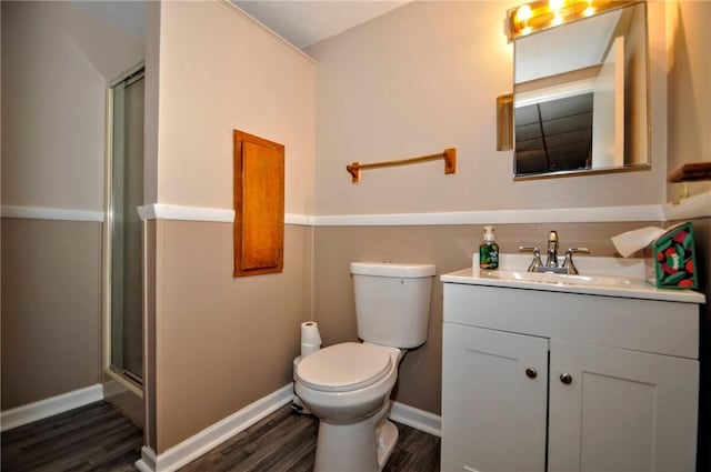 bathroom with toilet, a stall shower, vanity, wood finished floors, and baseboards