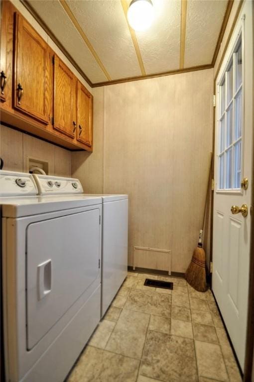 laundry room featuring a textured ceiling, separate washer and dryer, cabinet space, and crown molding