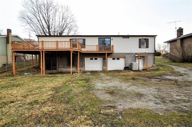 rear view of house with a deck, central AC unit, an attached garage, fence, and driveway