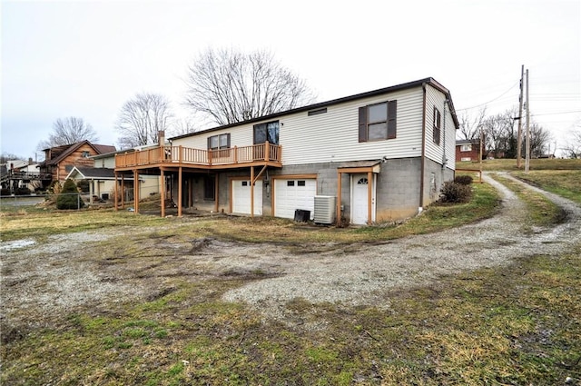 rear view of property with dirt driveway, central AC, a wooden deck, and a garage