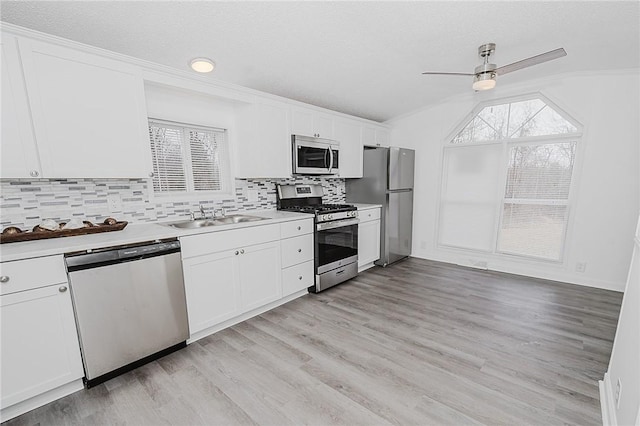 kitchen with white cabinets, light wood-style flooring, appliances with stainless steel finishes, light countertops, and a sink