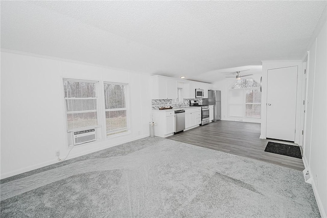 unfurnished living room with vaulted ceiling, ceiling fan, a textured ceiling, and baseboards