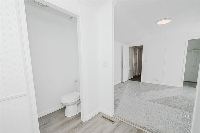 bathroom with baseboards, visible vents, toilet, and wood finished floors