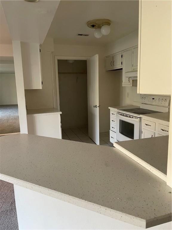 kitchen featuring light tile patterned floors, visible vents, and white range with electric stovetop