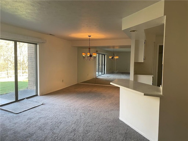 interior space featuring a chandelier, a textured ceiling, a wealth of natural light, and dark colored carpet