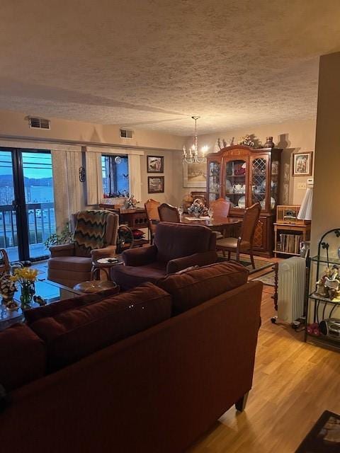 living area featuring light wood-style flooring, an inviting chandelier, visible vents, and radiator