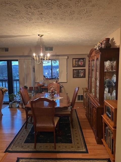 dining area with a chandelier, visible vents, and light wood finished floors