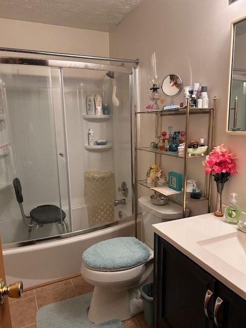 bathroom with bath / shower combo with glass door, toilet, a textured ceiling, vanity, and tile patterned flooring