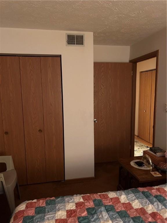 bedroom featuring a textured ceiling, visible vents, and a closet