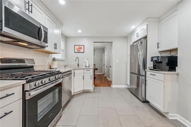 kitchen featuring light tile patterned floors, stainless steel appliances, light countertops, white cabinetry, and a sink