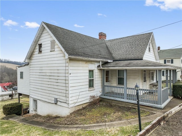 view of front of home with a porch, a chimney, and a shingled roof