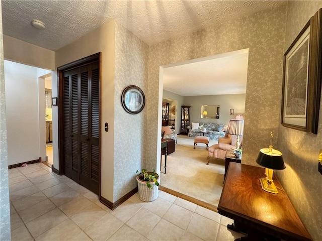 hallway with a textured ceiling, baseboards, and wallpapered walls