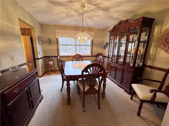 dining room featuring light carpet, a textured ceiling, and a notable chandelier