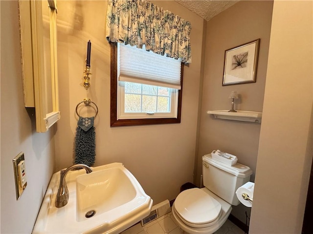 half bathroom with a sink, toilet, and baseboards