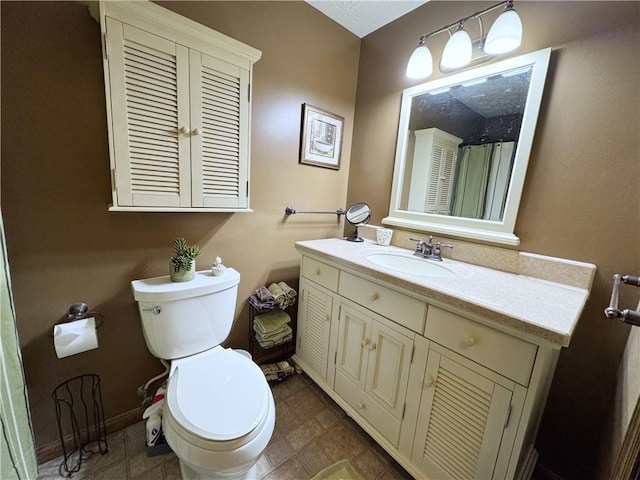 bathroom featuring toilet, baseboards, and vanity