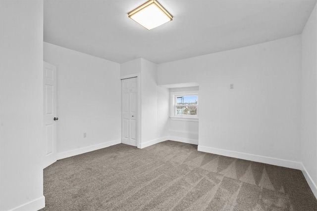 spare room with dark colored carpet and baseboards