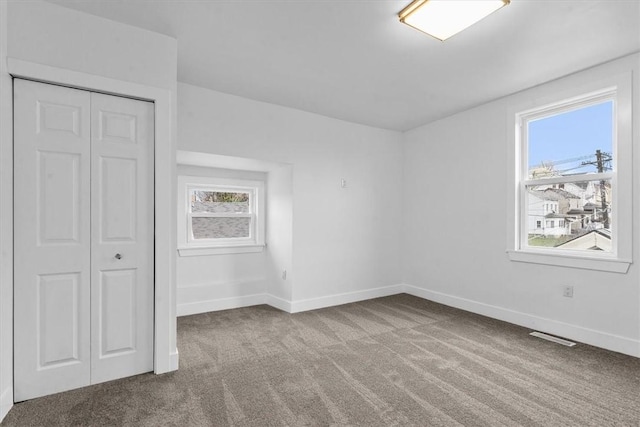 unfurnished bedroom featuring visible vents, a closet, baseboards, and carpet flooring