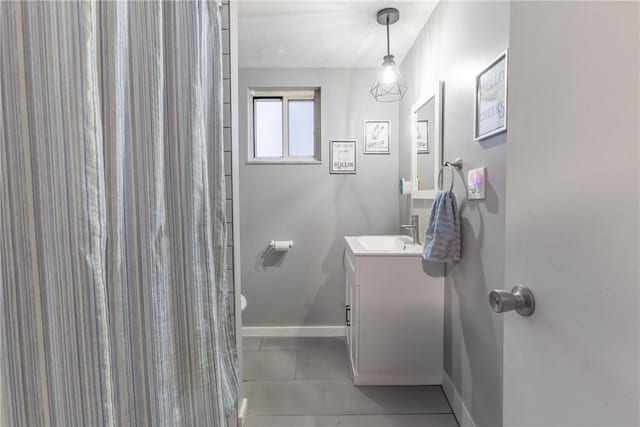 bathroom featuring curtained shower, vanity, baseboards, and tile patterned floors