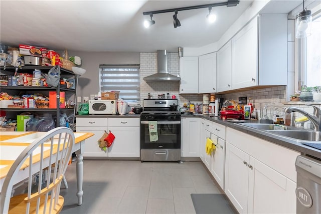 kitchen with white cabinets, decorative backsplash, wall chimney exhaust hood, appliances with stainless steel finishes, and a sink