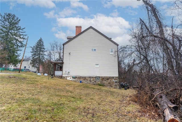 view of property exterior with a sunroom, a chimney, and a lawn