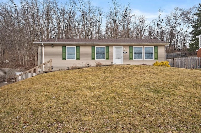 ranch-style house featuring fence and a front yard