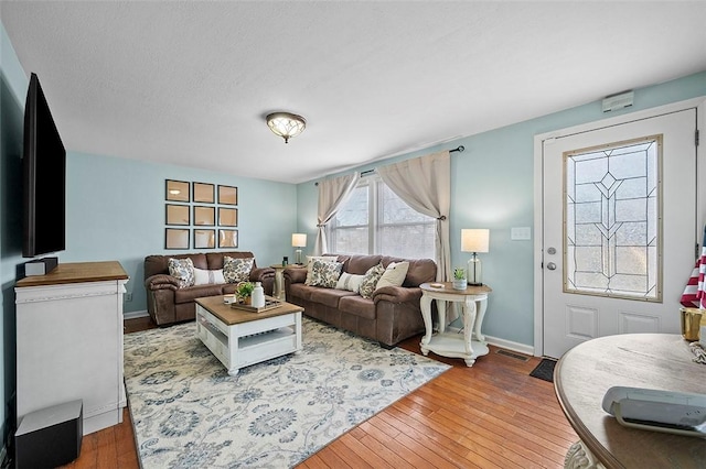 living area with wood-type flooring, visible vents, and baseboards