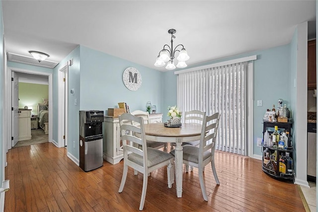 dining room with an inviting chandelier, baseboards, and hardwood / wood-style flooring