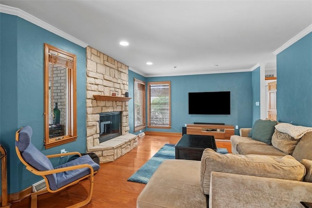 living room featuring a stone fireplace, recessed lighting, wood finished floors, baseboards, and ornamental molding