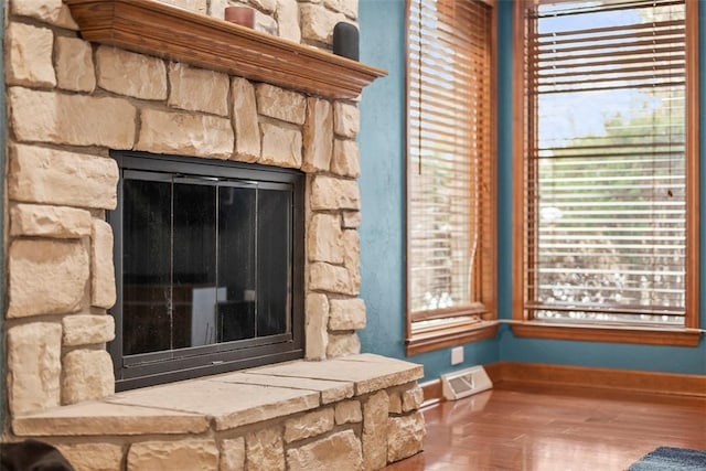 details featuring baseboards, a fireplace, visible vents, and wood finished floors