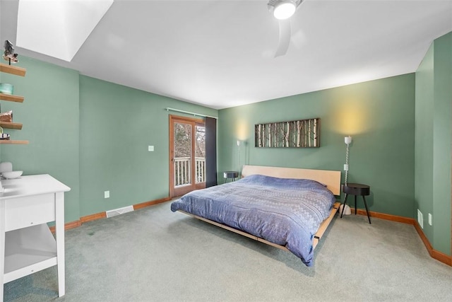 carpeted bedroom with access to exterior, a skylight, visible vents, and baseboards