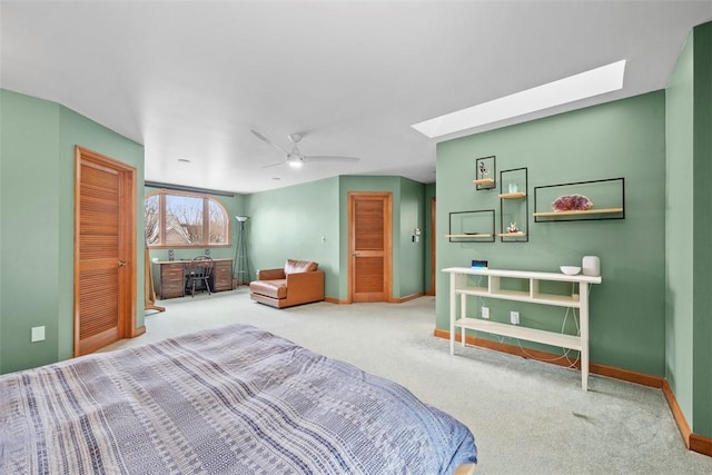 carpeted bedroom with a ceiling fan, a skylight, and baseboards