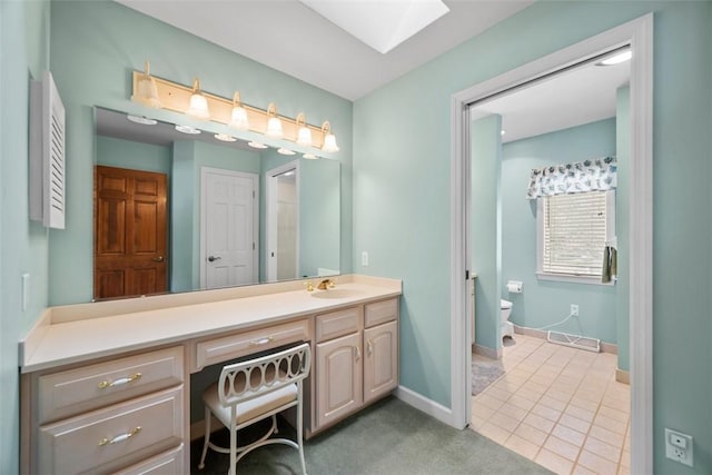 bathroom featuring a skylight, visible vents, baseboards, toilet, and vanity