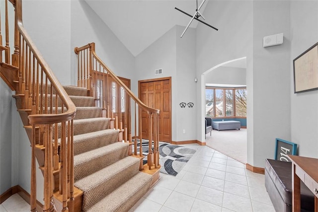 entrance foyer featuring arched walkways, light tile patterned flooring, visible vents, baseboards, and stairs