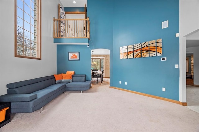 living room with arched walkways, a high ceiling, carpet flooring, and baseboards