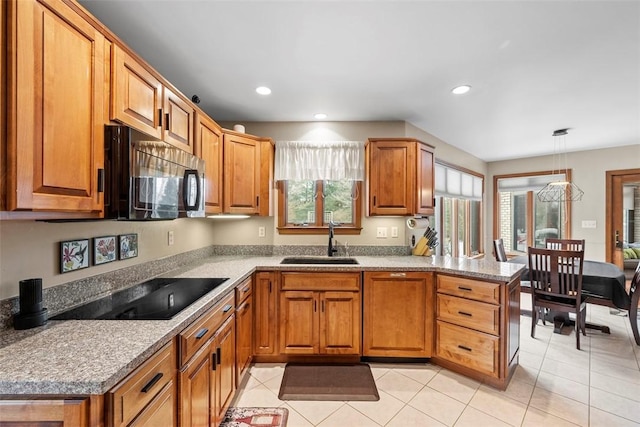 kitchen featuring a peninsula, plenty of natural light, a sink, and black electric cooktop